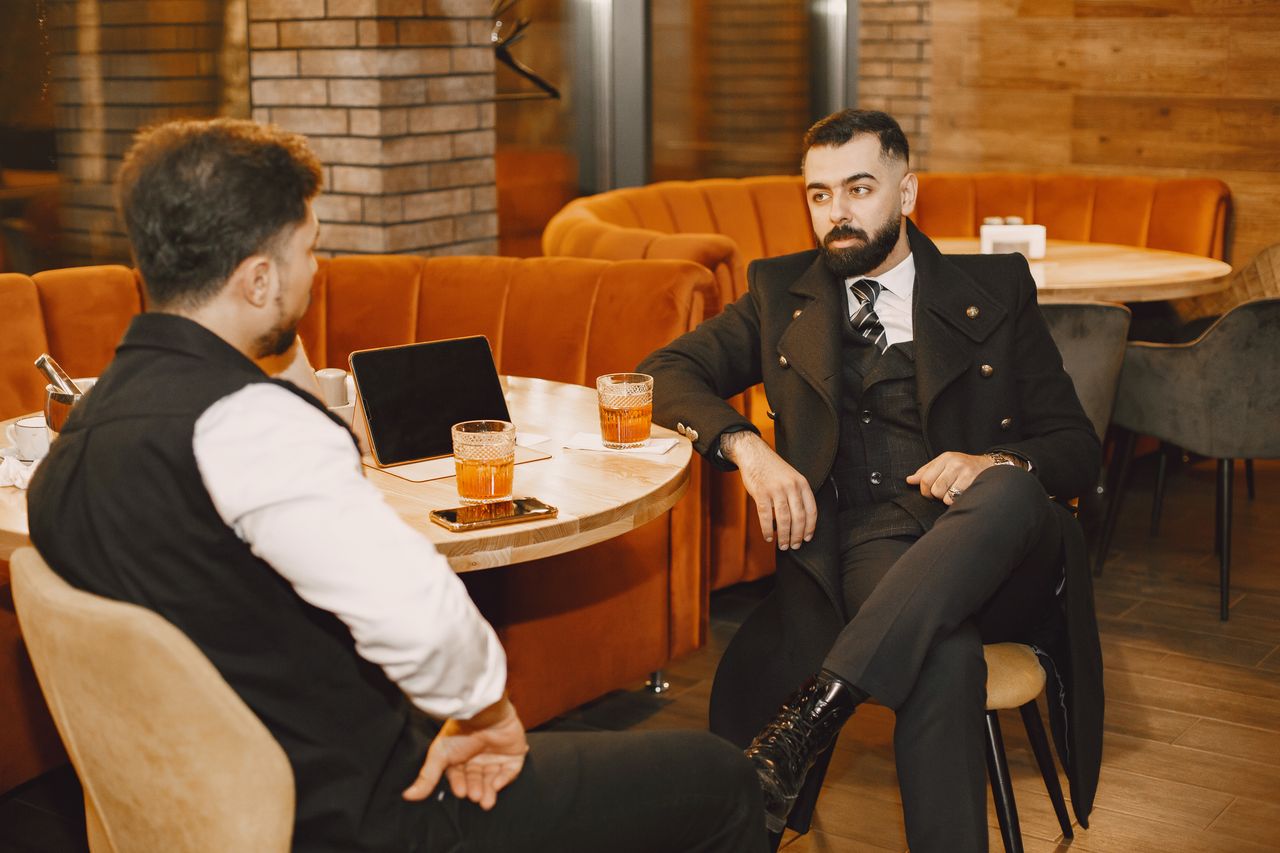 product-01 Two businessmen having a relaxed discussion in a stylish cafe setting.